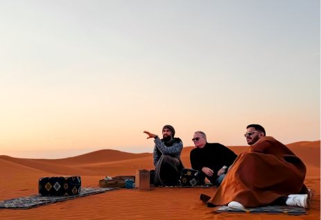 A group settling onto the red dunes as the light goes