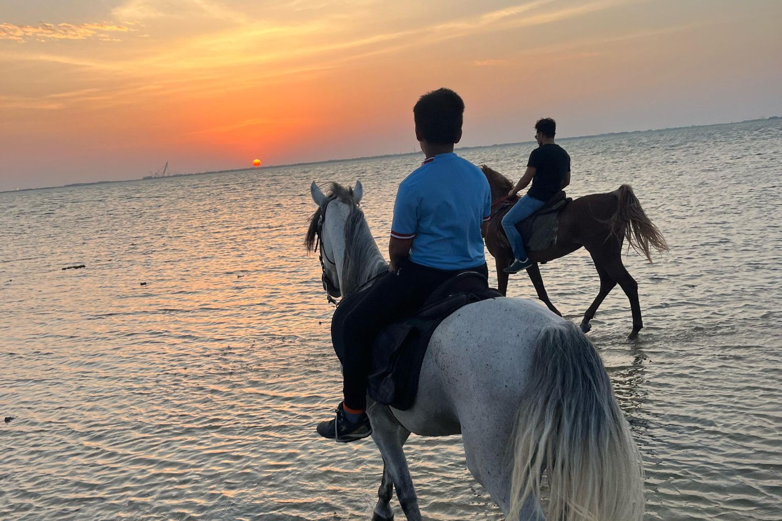 Children riding horses through the shallows on a Jeddah beach