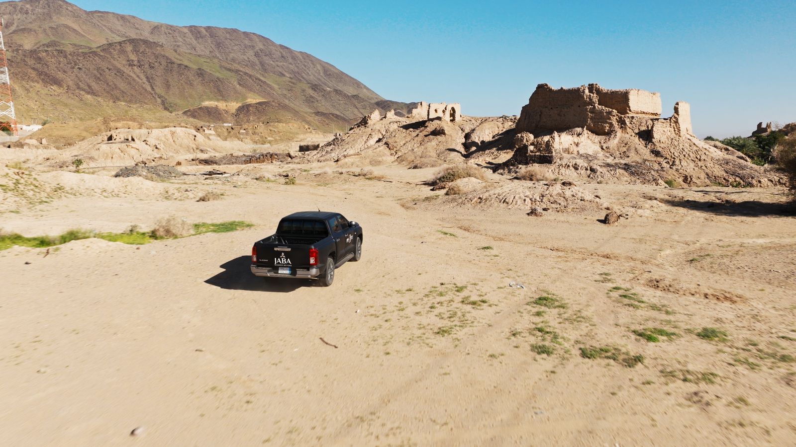 An expedition vehicle passing the old fort at Yanbu Al Nakhal